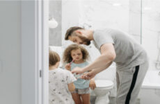 padre ayudando a sus hijos a lavarse los dientes