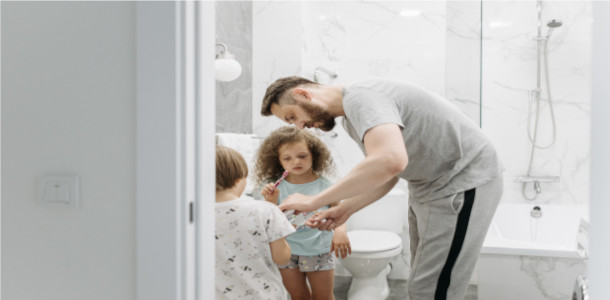 padre ayudando a sus hijos a lavarse los dientes